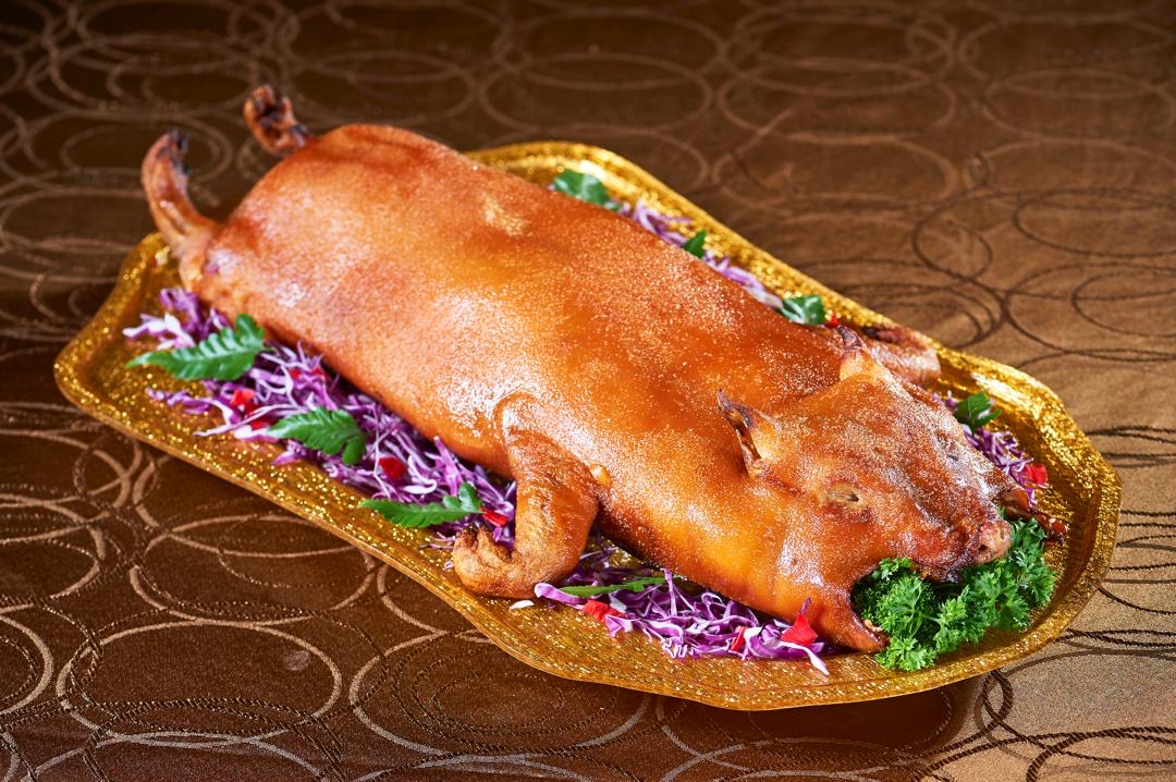 Signature roast suckling pig on a gilded platter